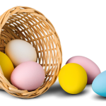 A small, colorful Easter basket filled with assorted, brightly colored eggs. The basket is also decorated with a yellow ribbon.